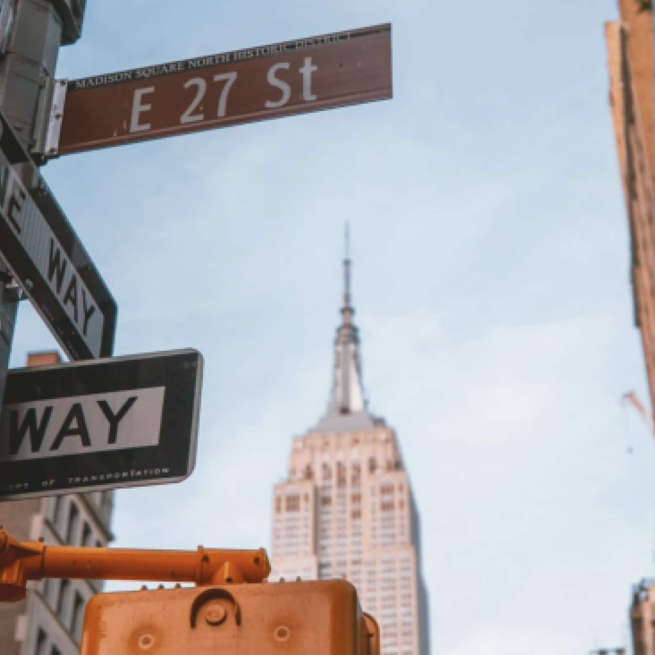 Street signs in the foreground in downtown New York and the Empire State building in the background. 