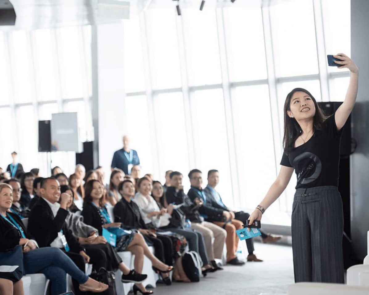 An event presenter taking a selfie with the seated audience at a Xero small business event.