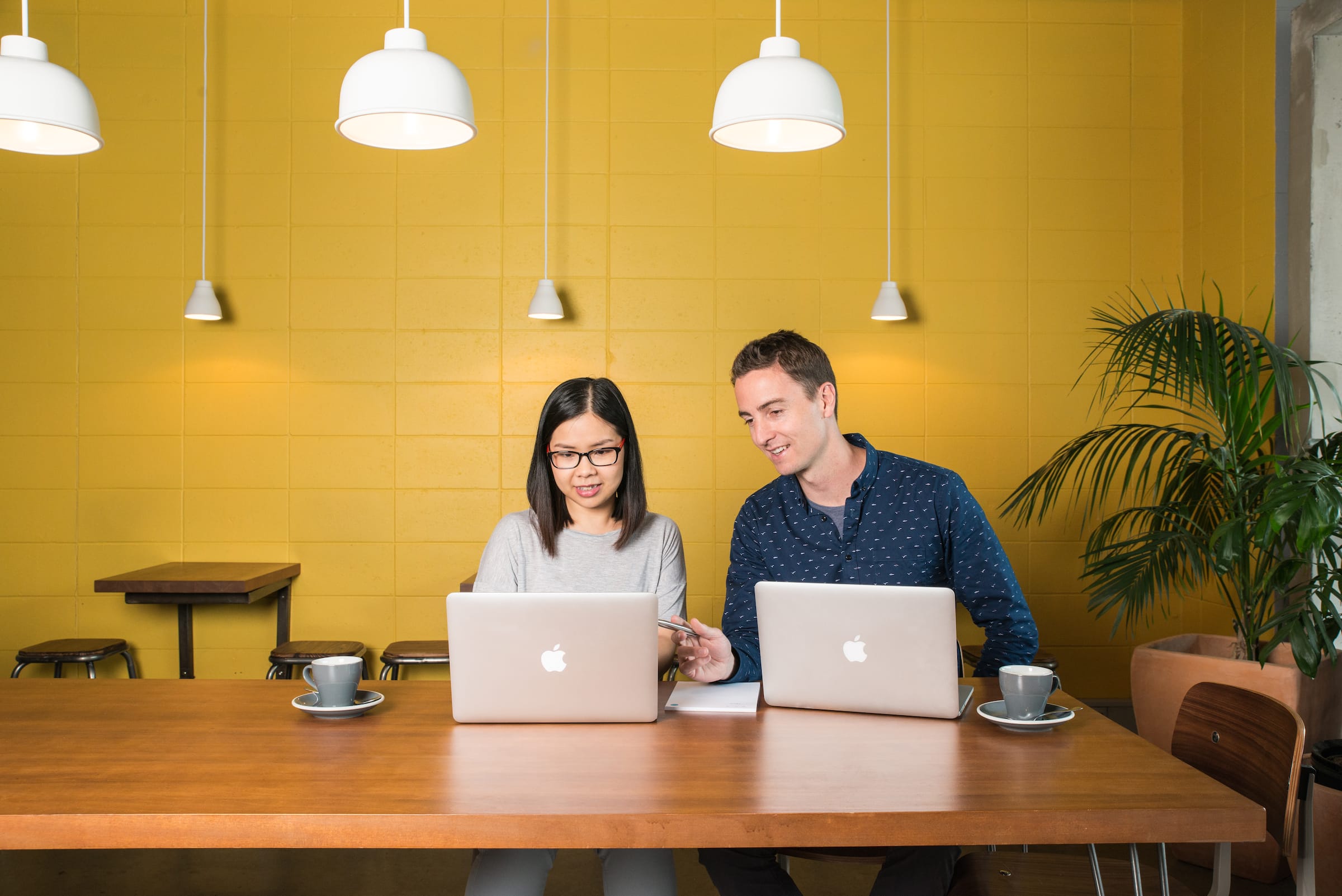 Image of two people working on their laptops