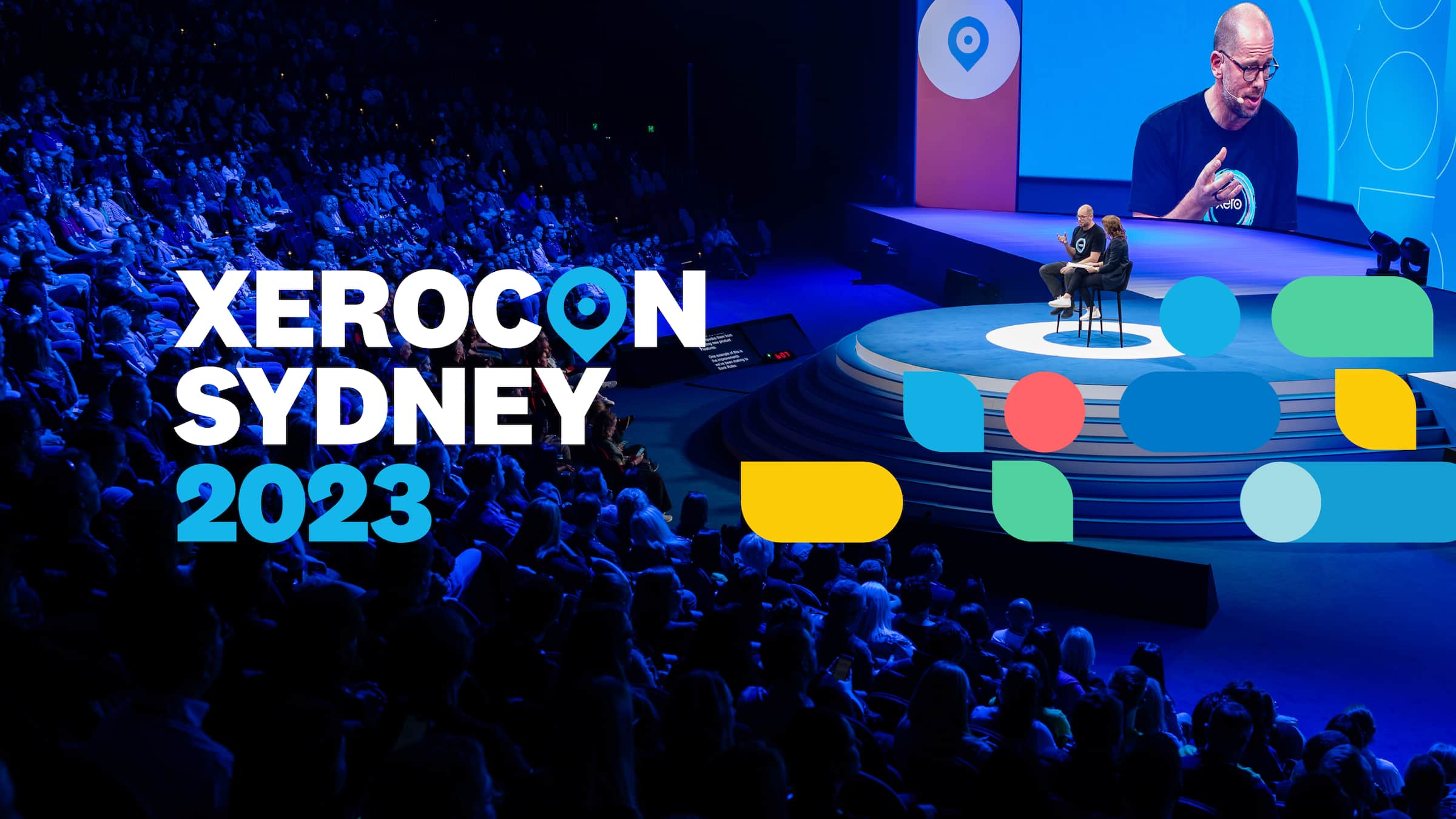 A group of people in the audience at Xerocon smile and applaud a speaker.