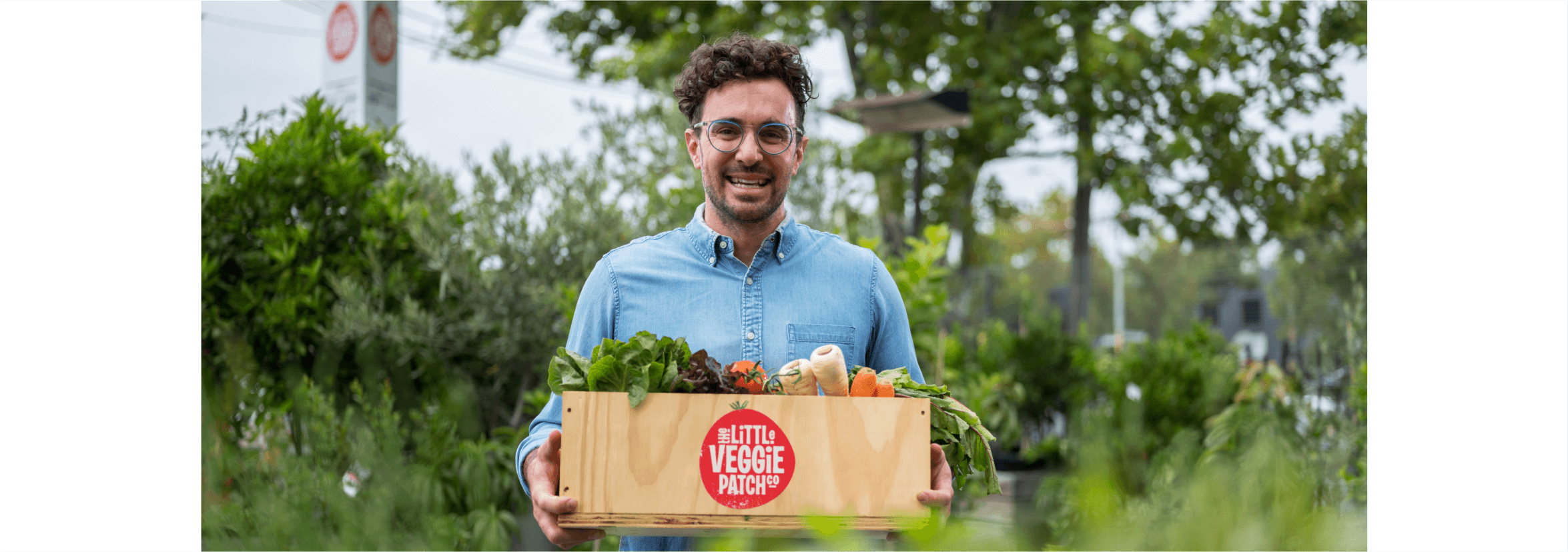 A business owner smiles and holds up a box of vegetables as they consider signing up for a free trial with Xero.