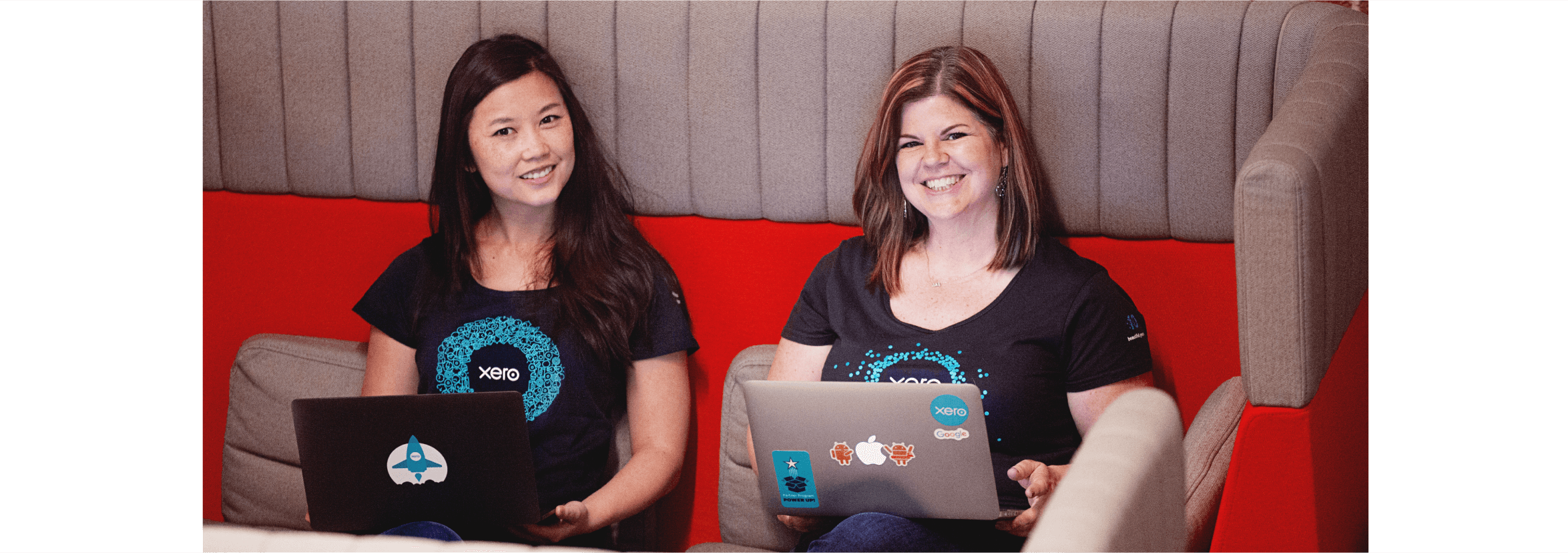 Two Xero team members smile while holding their laptops, happy with their career choices to join Xero.