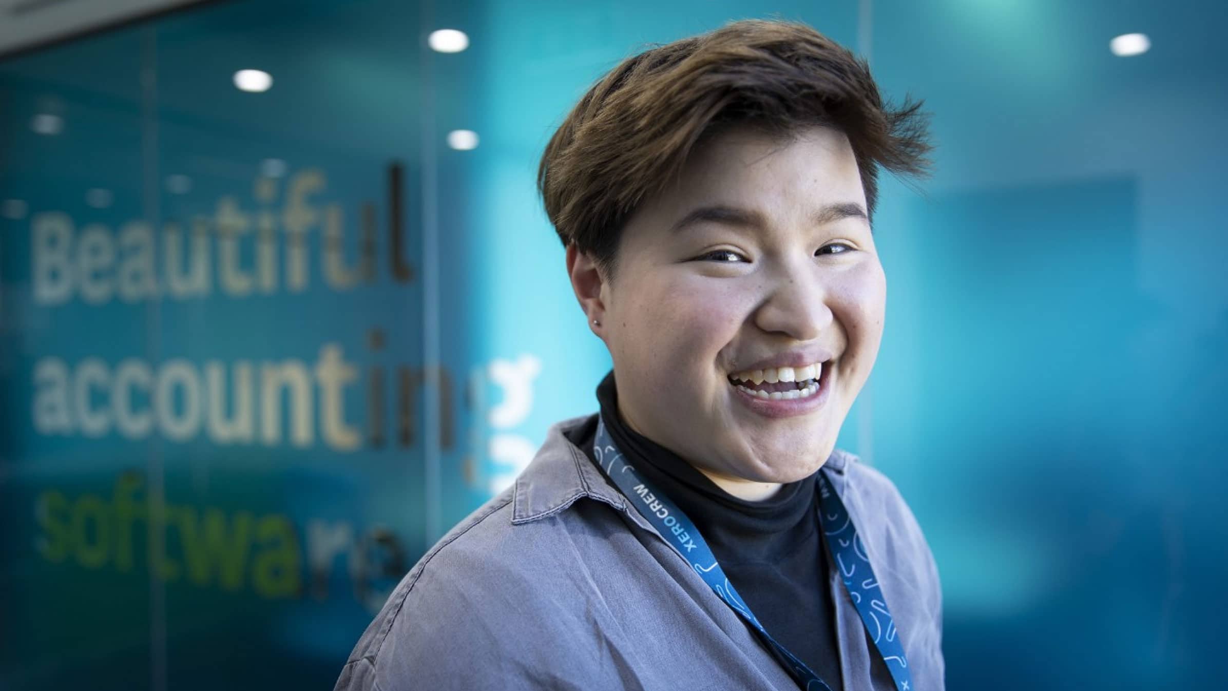 Grace Tai, a product designer at Xero, is all smiles in front of blue doors that say ‘Beautiful accounting software’.