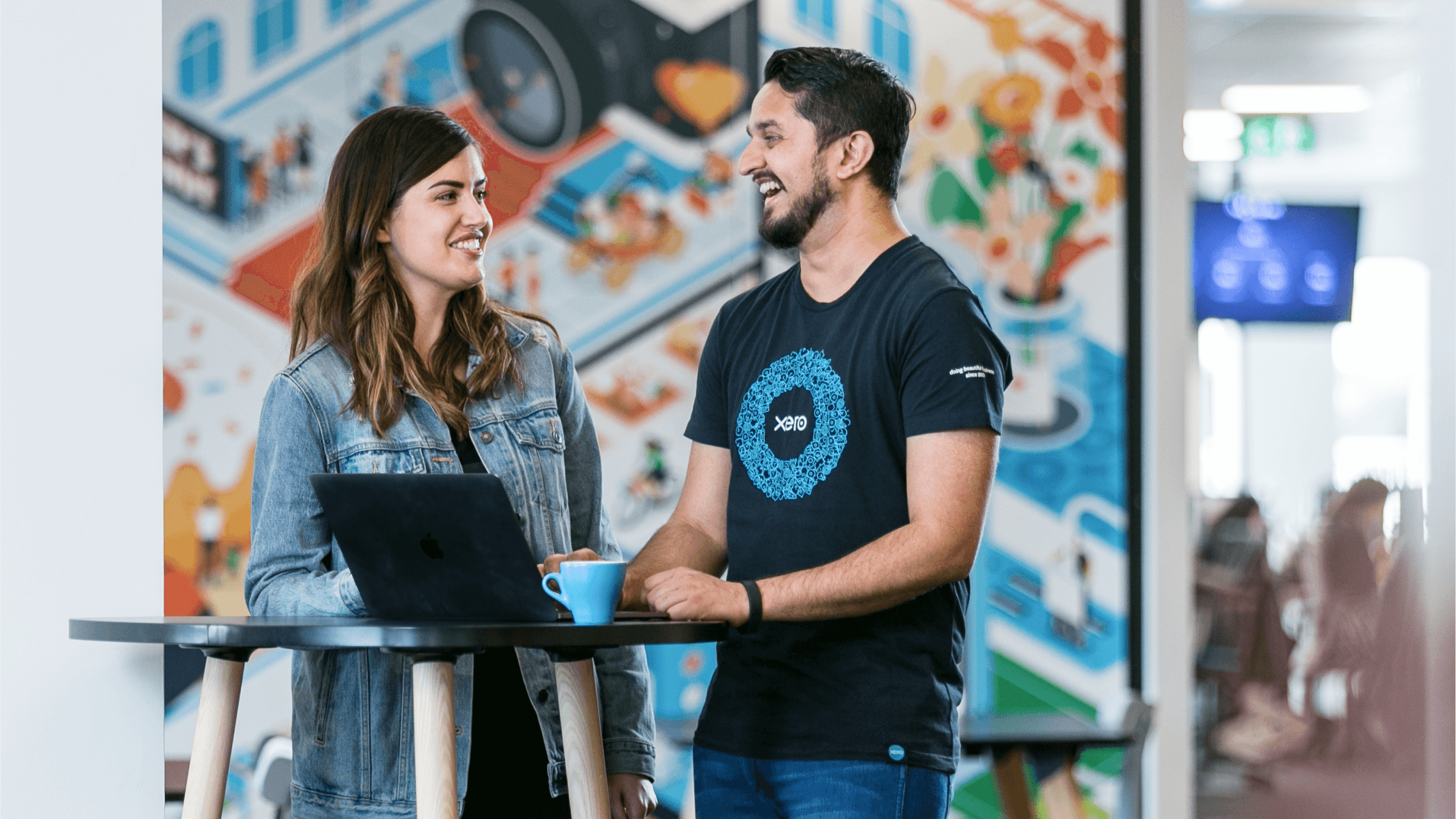 Two Xero employees discuss work over a coffee at one of Xero’s vibrant offices. 
