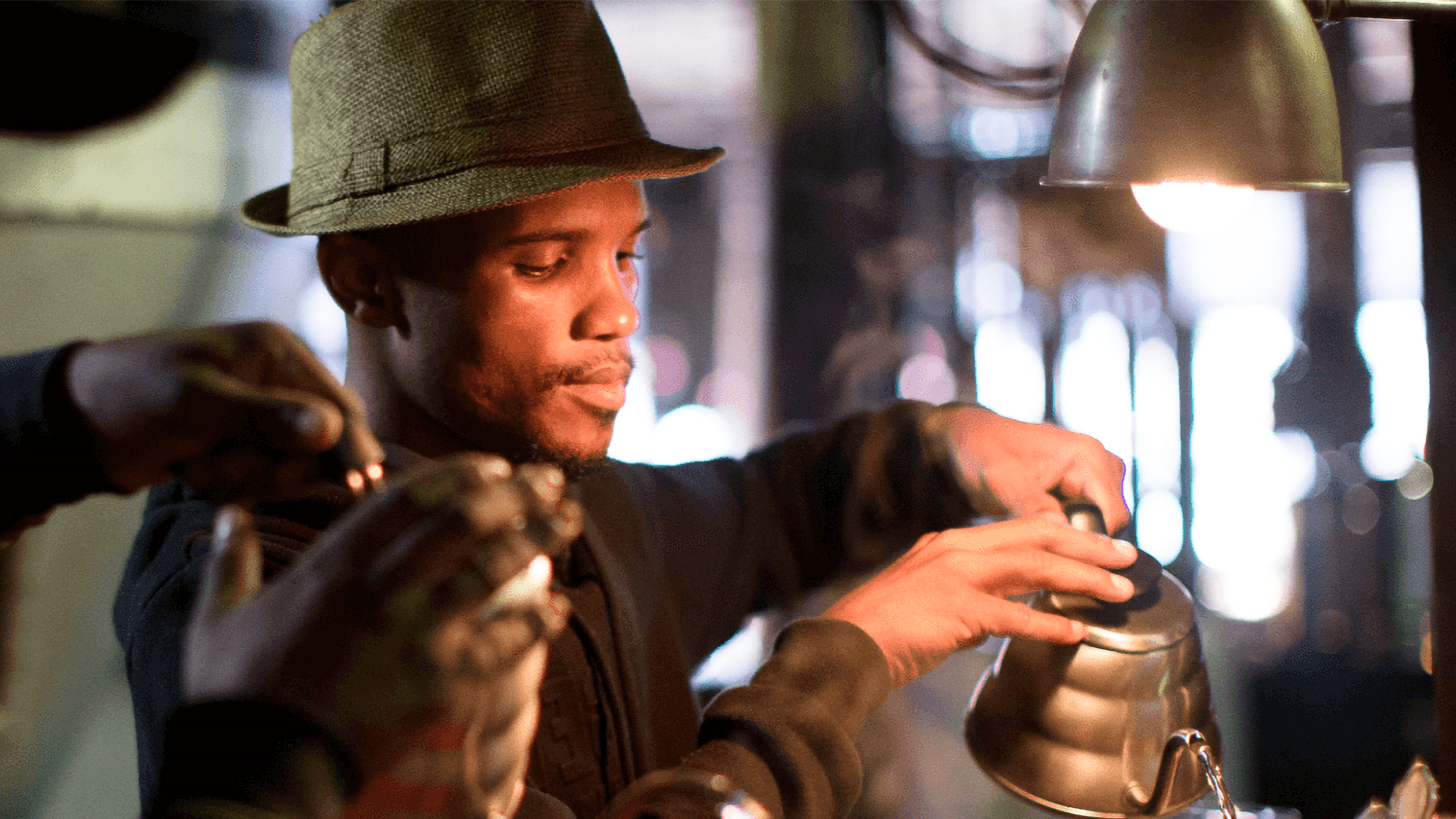 A staff member at a cafe pouring hot water from a teapot.