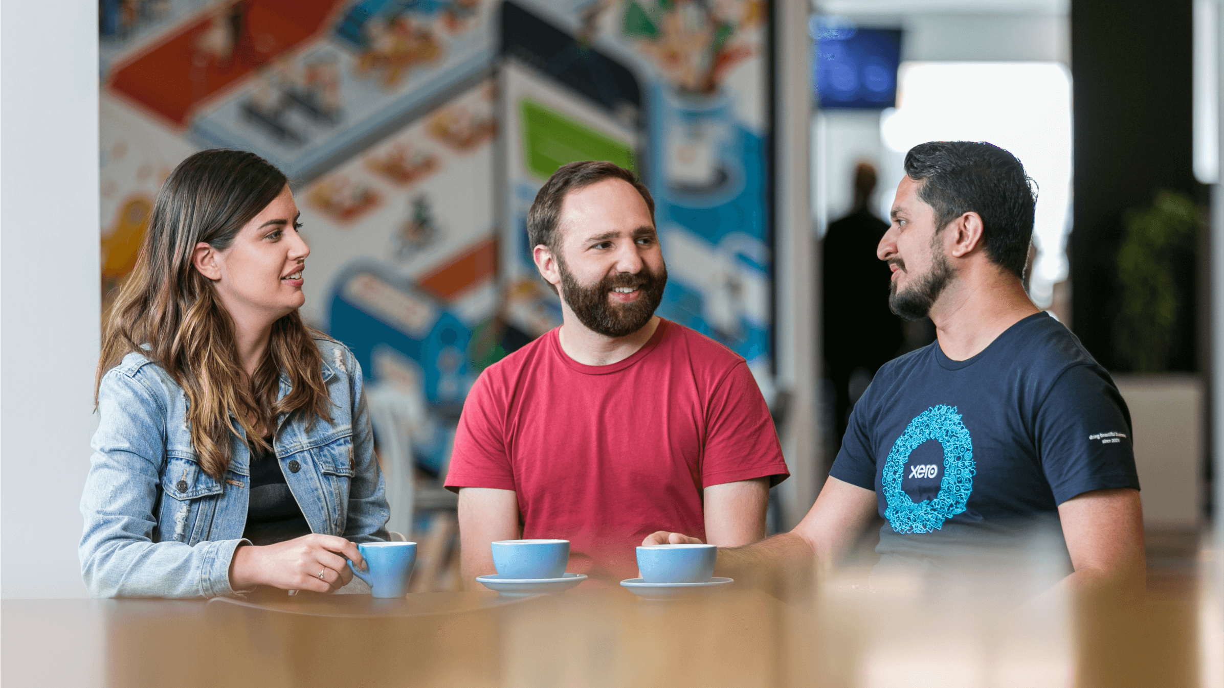 Two Xero accountants chat to a Xero team member over a cup of coffee. 