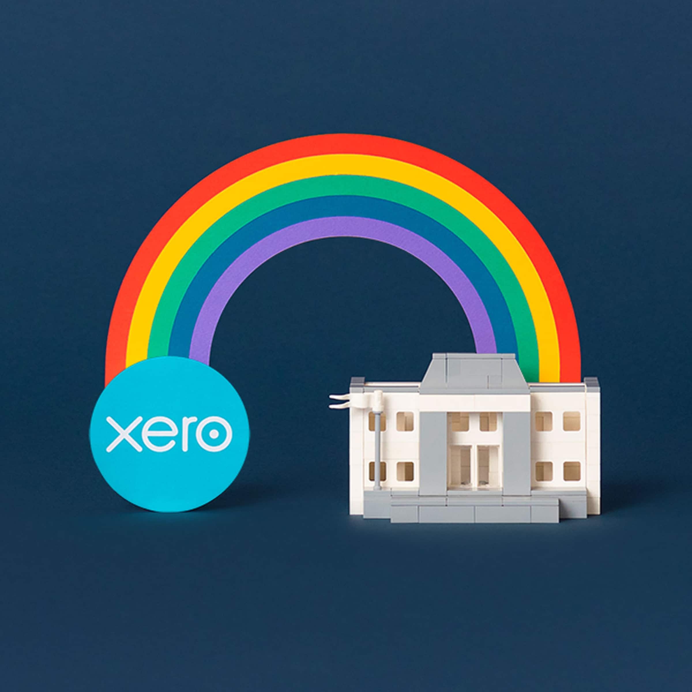A semi-circular rainbow arches between an old-style bank building and the Xero logo.