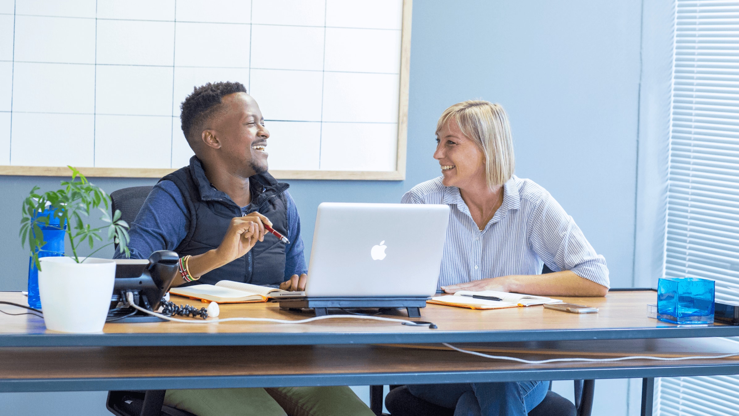 An accountant talks through their year-end workflow with a colleague in front of an open laptop.