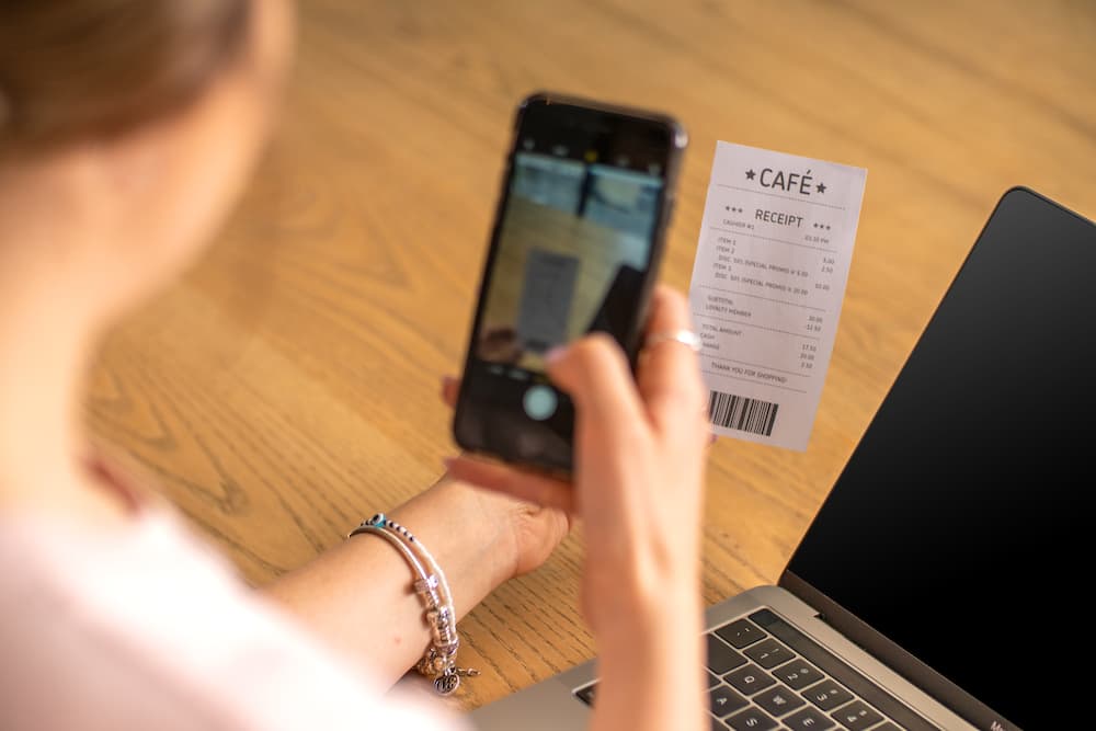 Person using a smartphone to scan a cafe receipt for expense tracking.