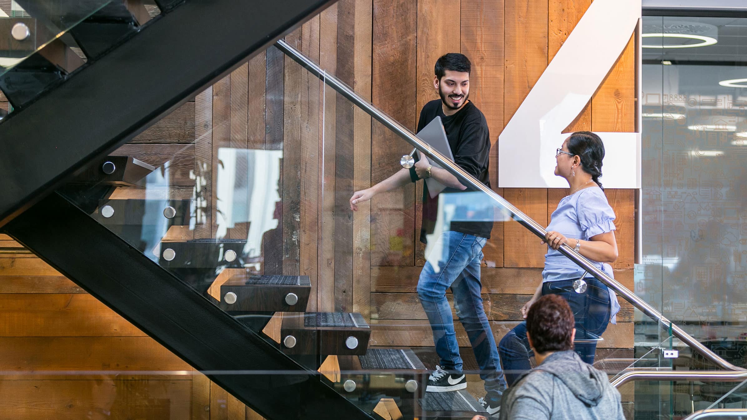 Two employees discuss a project they’re working on while climbing the stairs at their office.