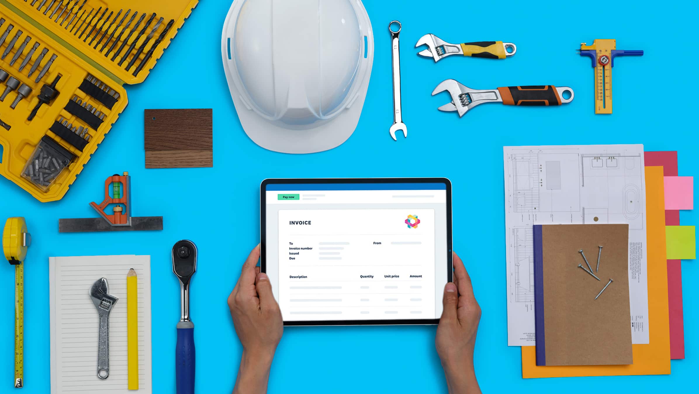 Hands holding a tablet that displays completed invoice, on top of a workbench.