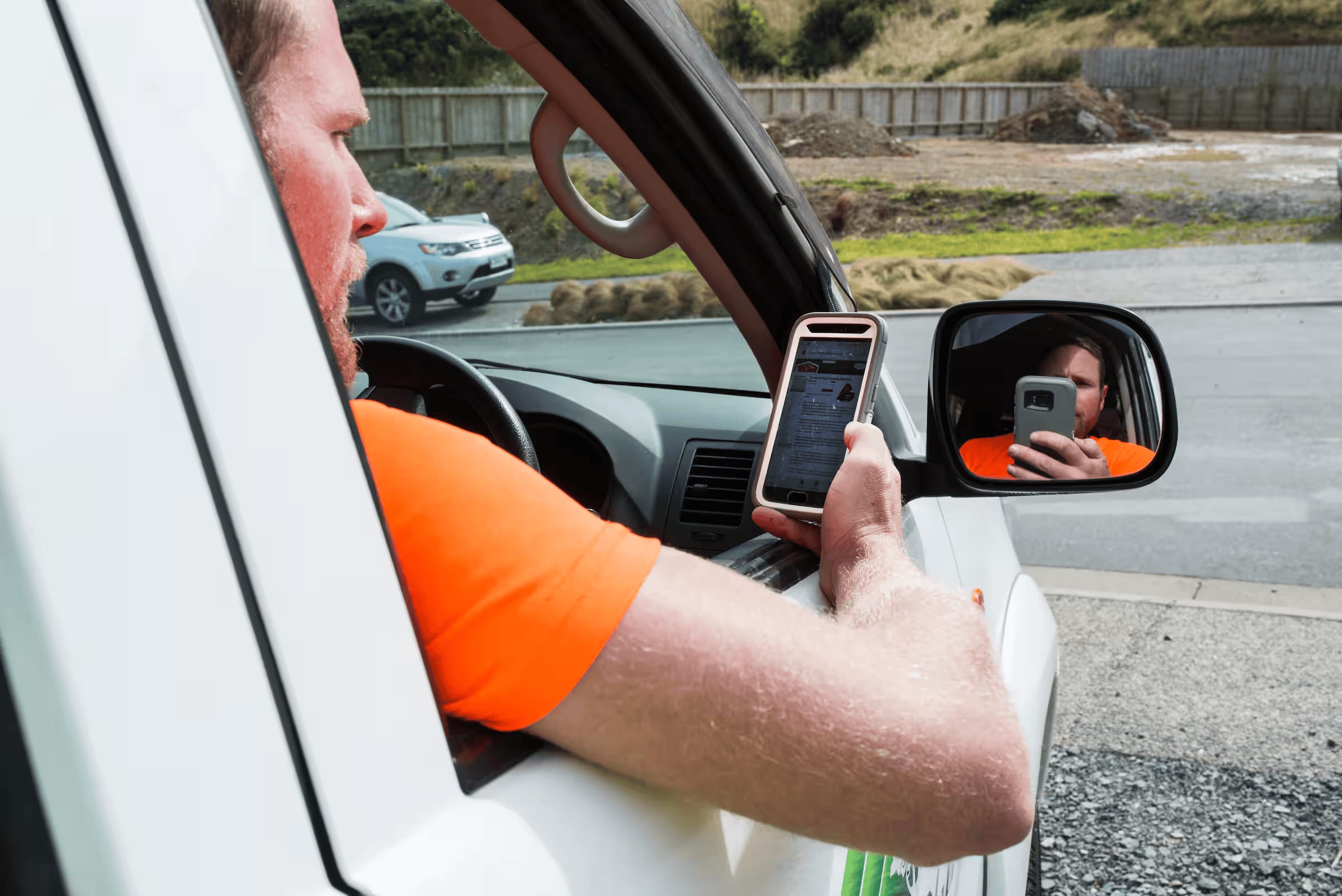 A contractor using Xero on his phone while parked in his ute.