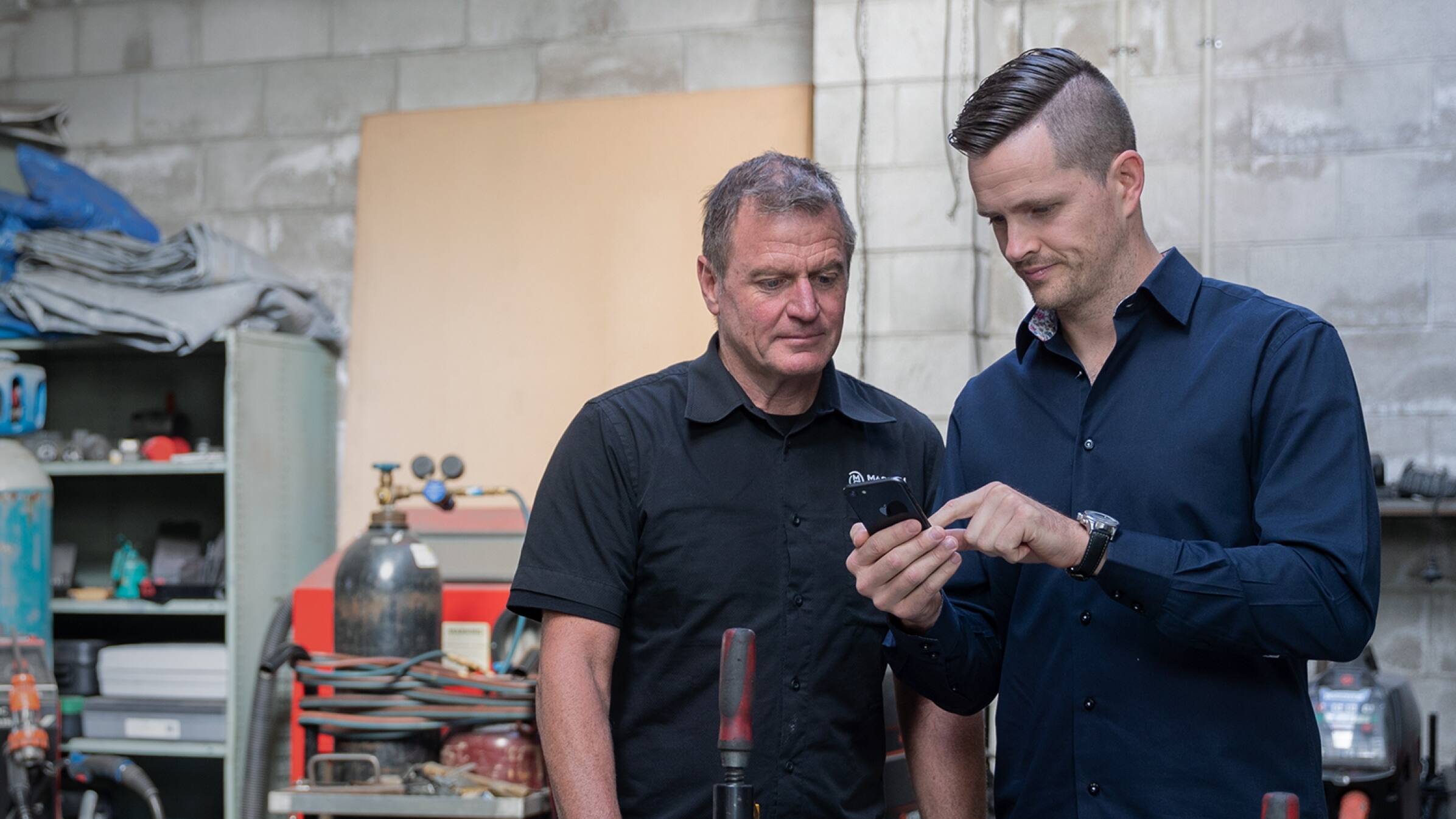 A cloud integrator and a factory owner look at a tablet as they discuss what solutions the business needs. 