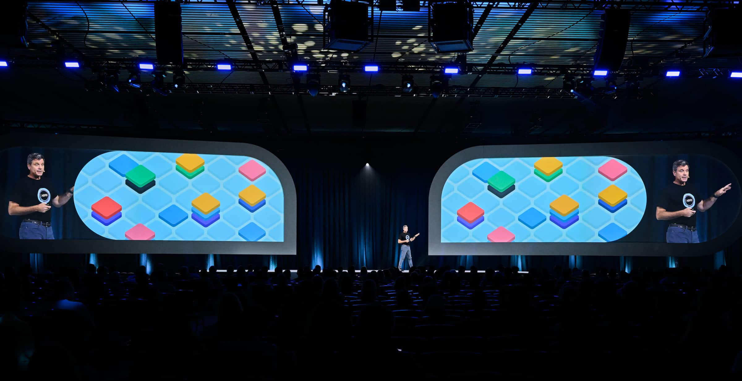 Xero CEO Steve Vamos talks to a large audience with a background displaying the word ‘Human’ in large pink letters behind him
