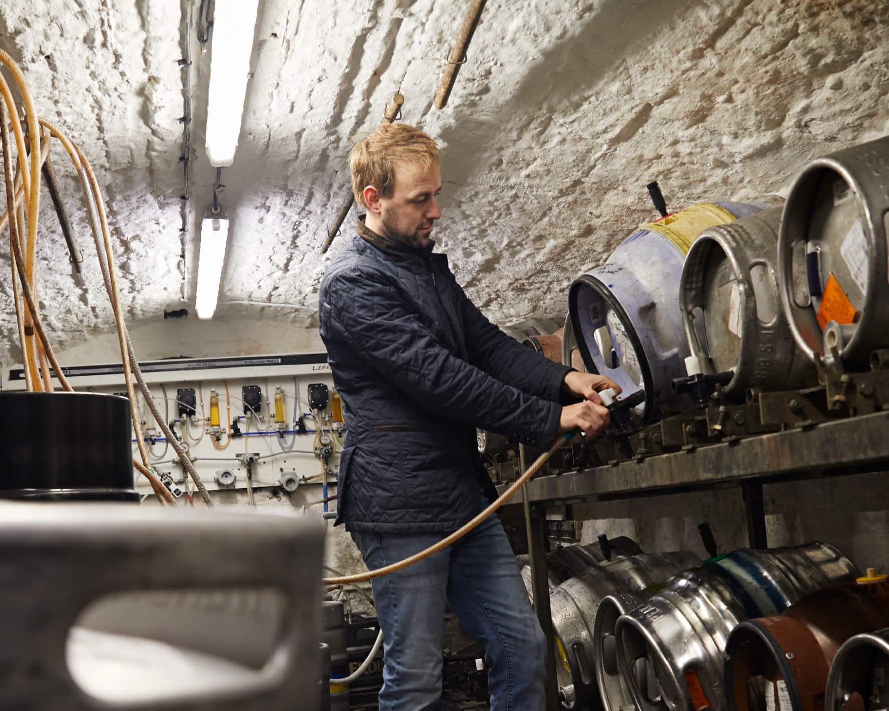 A person filling a beer keg in a brewery.