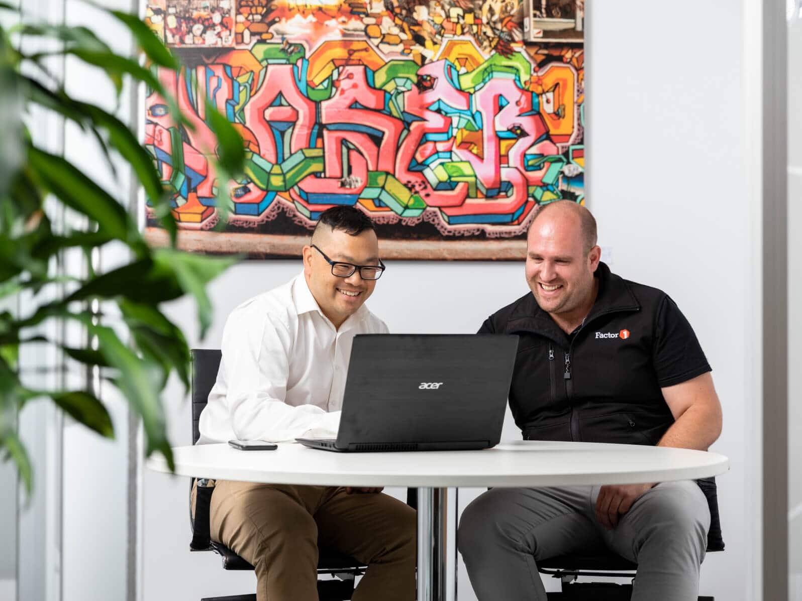 Two people using a laptop in a modern office