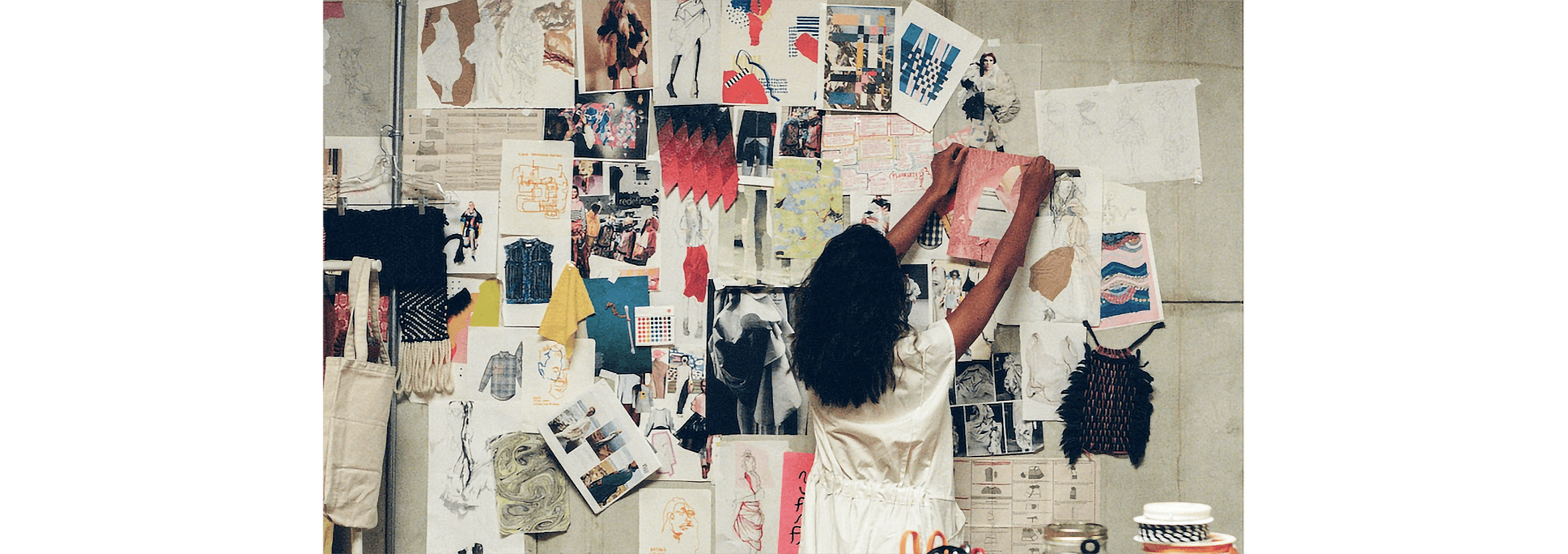 An artist pins one of their latest works on a wall in their studio.