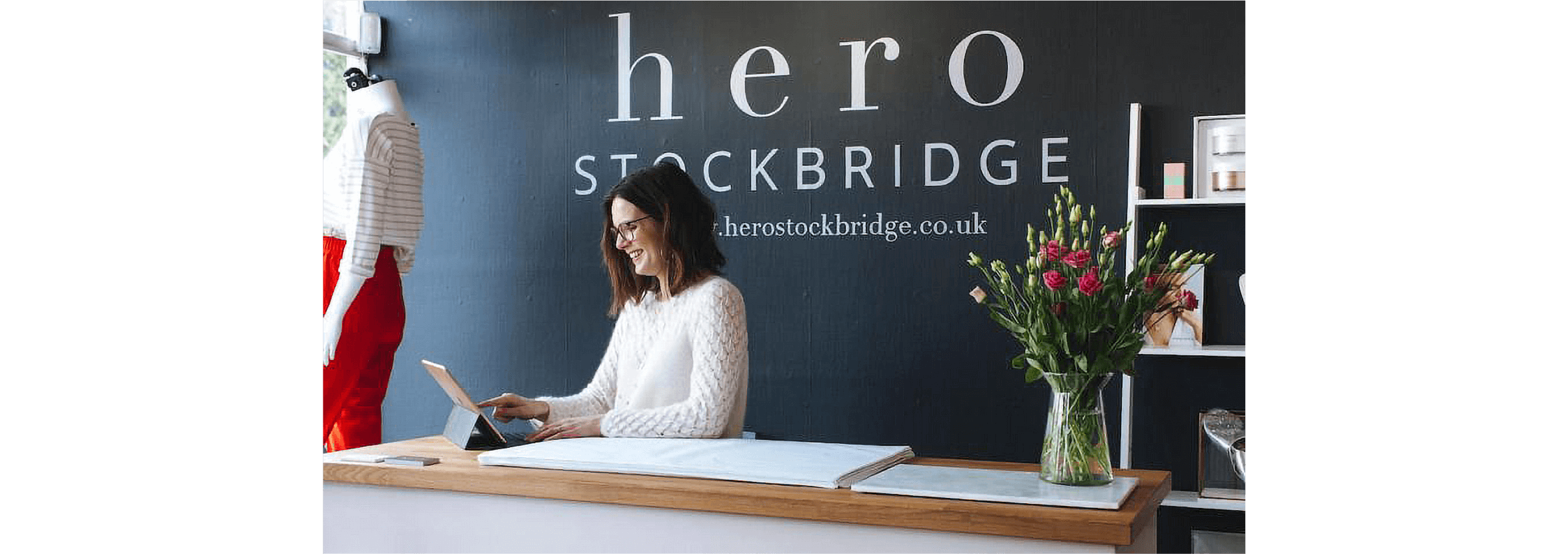 An office manager works from their tablet at the reception desk of a business.