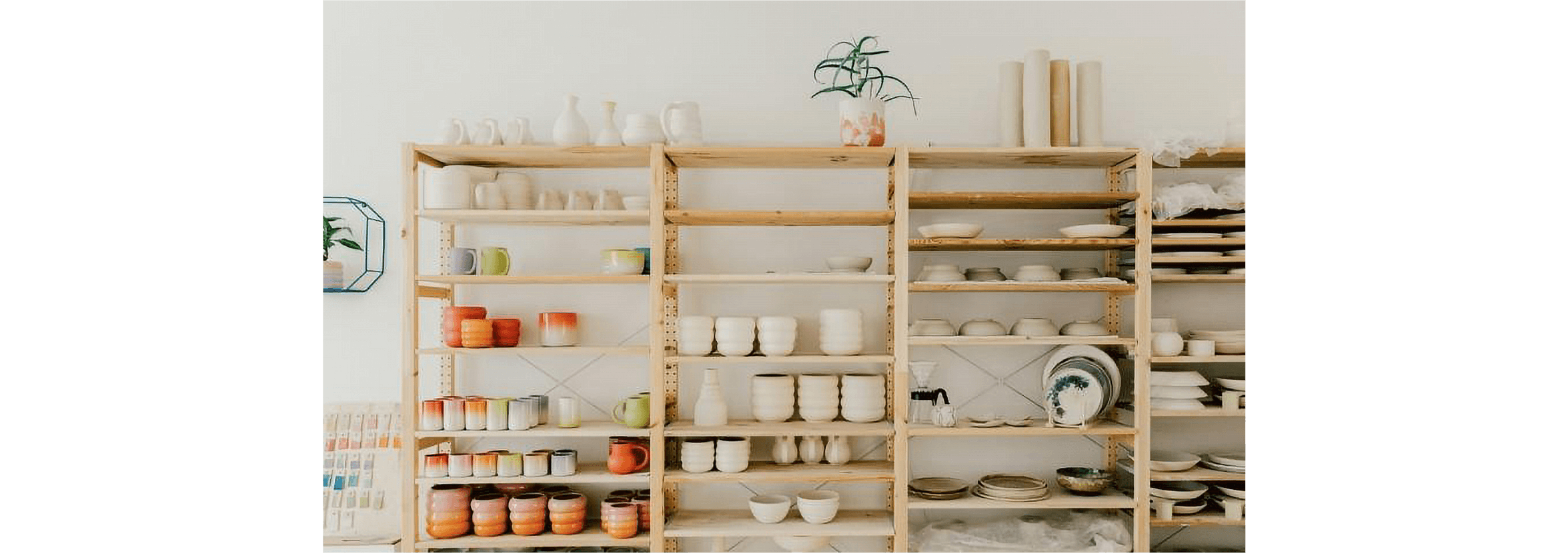 A set of shelves lined with mugs, plates and other crockery.