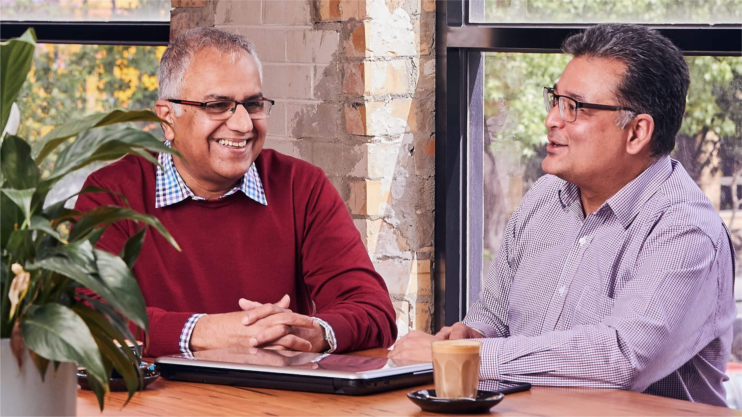  A business owner and accountant sit at a meeting room table talking.