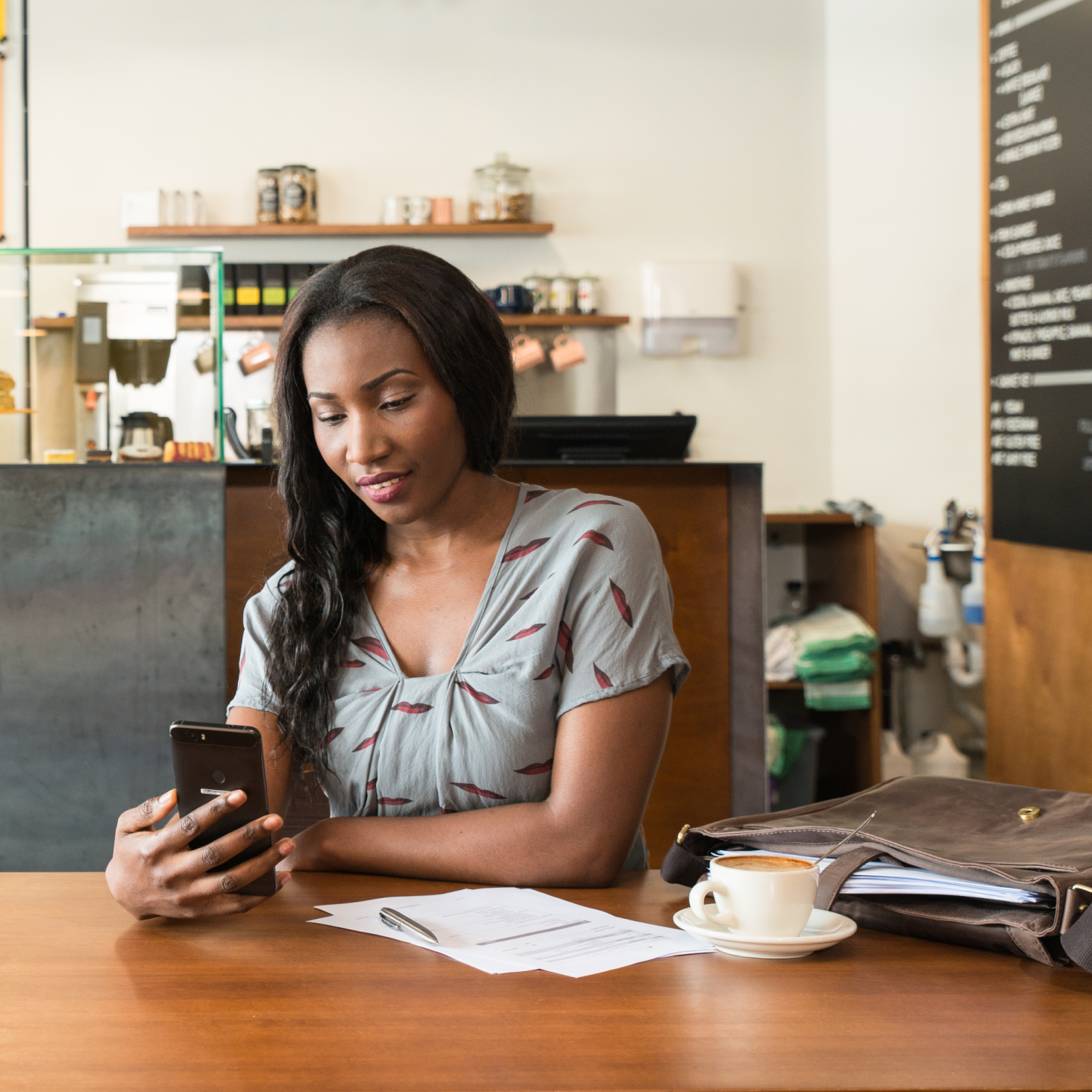 The manager of a charity reviews the accounts on their phone while having coffee at a cafe.