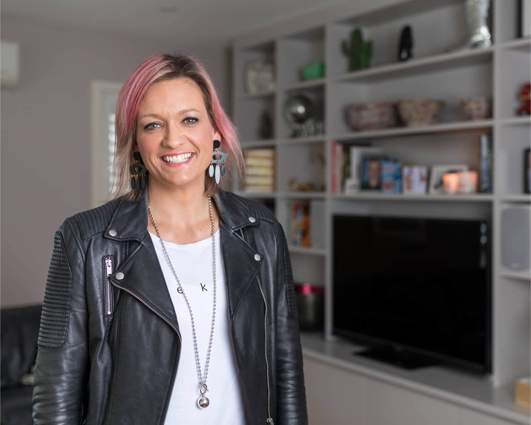 A smiling real estate agent stands in the living room of a property that’s on the market.