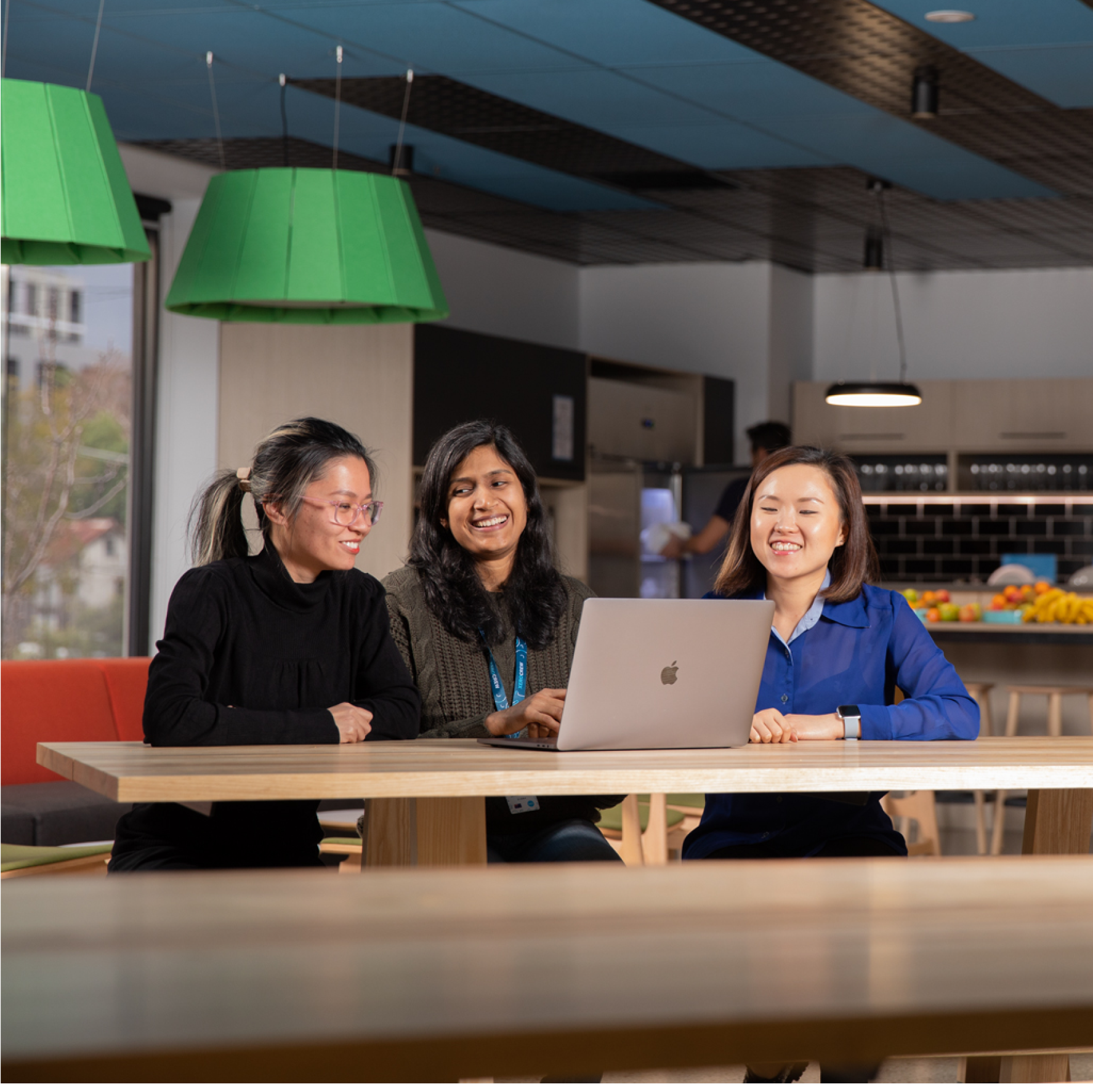 Three Xeros sit around a laptop in an informal meeting to discuss project progress.