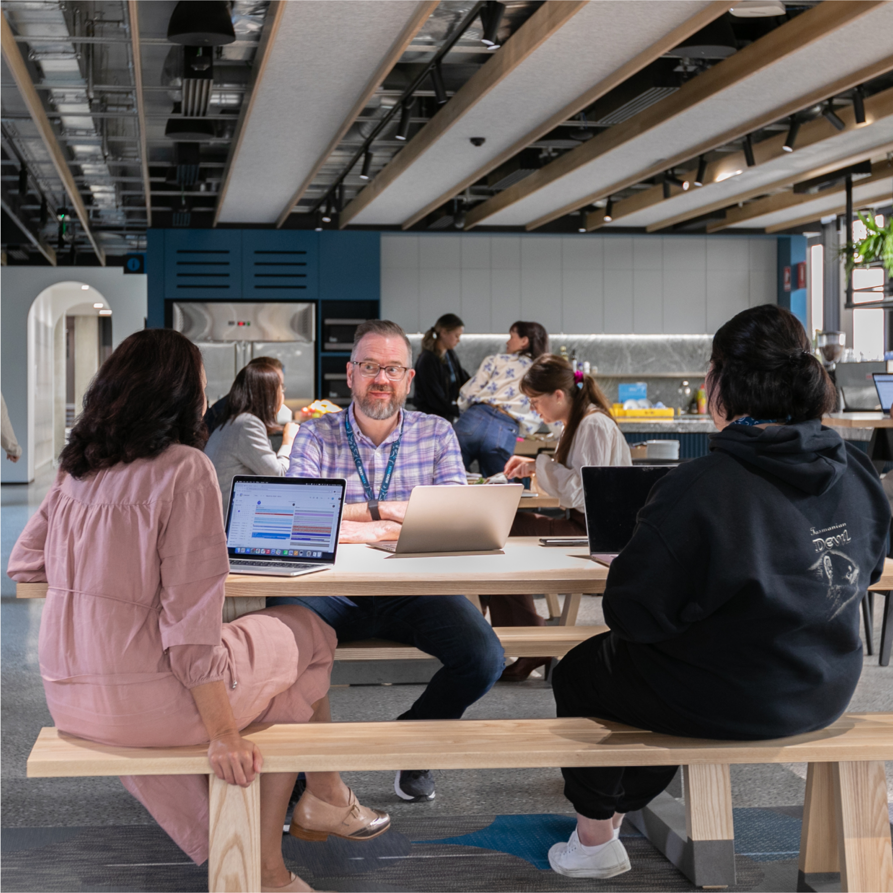 Three Xero employees from diverse backgrounds sit at a table chatting.