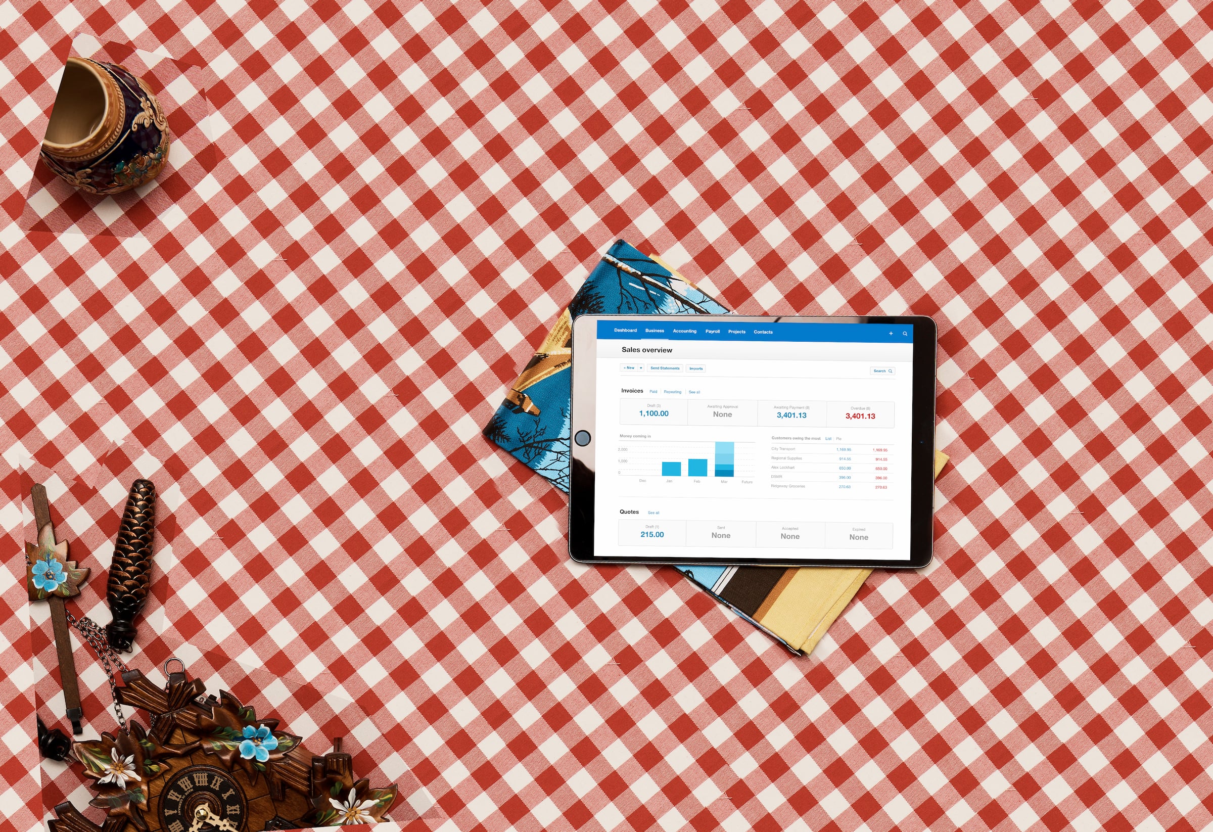 A Xero sales overview screen is open on an ipad that’s lying on a tablecloth checkered red and white.