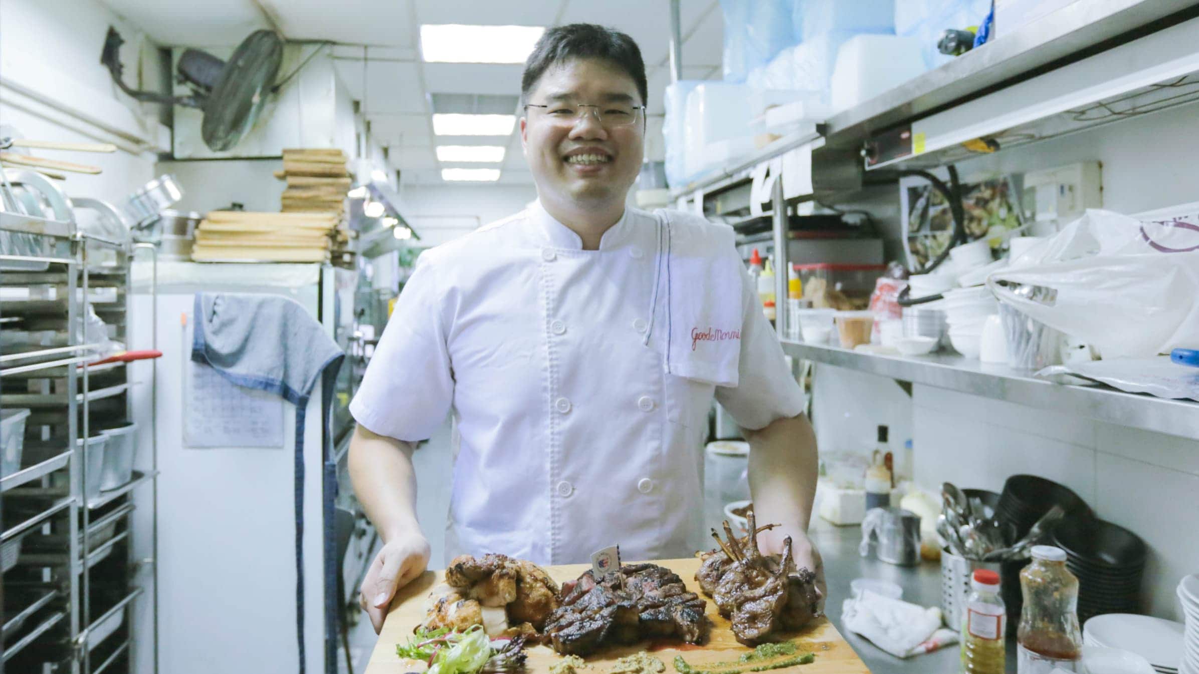 Garang Grill chef Jeremy Cheok standing in his kitchen with freshly cooked meat on a serving board.