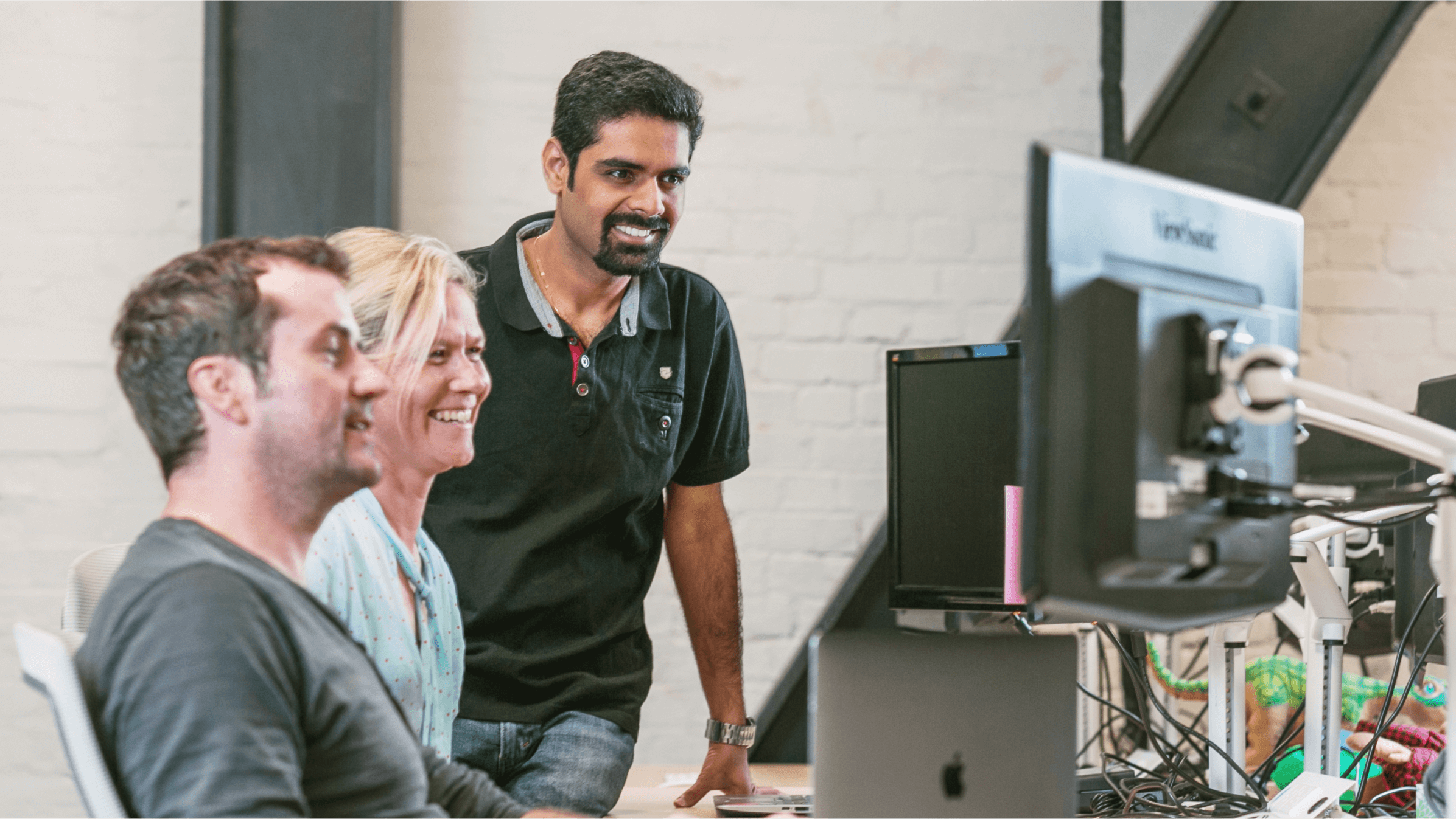 Two Xero employees and their manager look at a computer screen, considering their reply to an online enquiry.